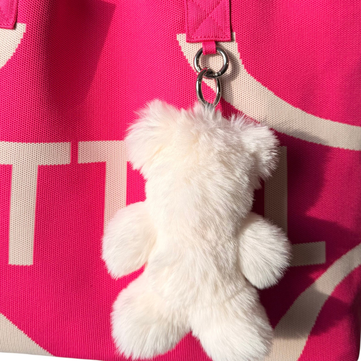 UTTAL Cream Plushy Teddy Bag Charm attached to a pink knitted tote bag