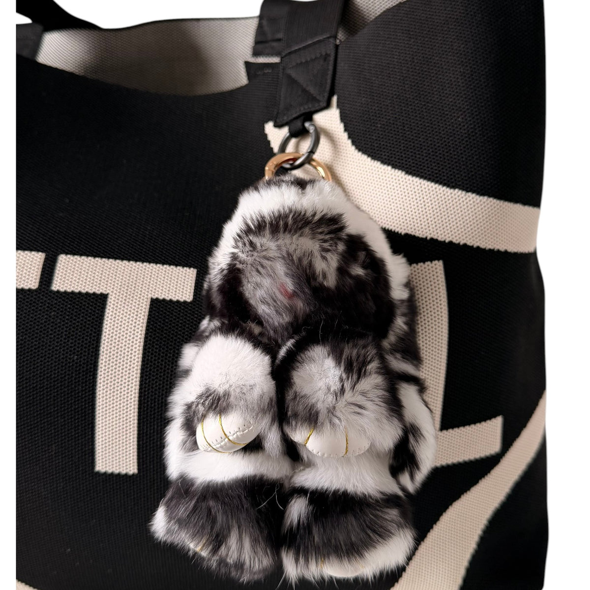 UTTAL Mono Plushy Bunny Bag Charm attached to a black knitted tote bag